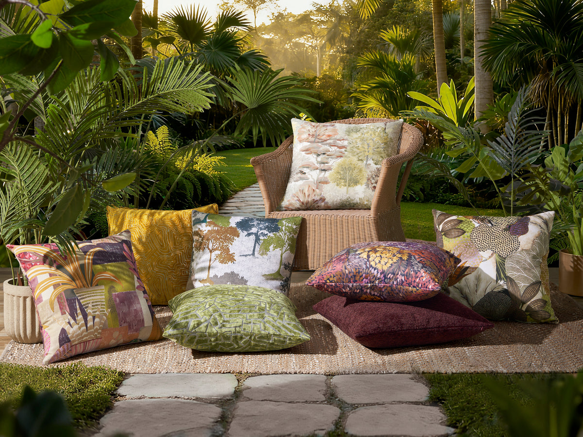 Botanical print pillows on a garden bench and lawn