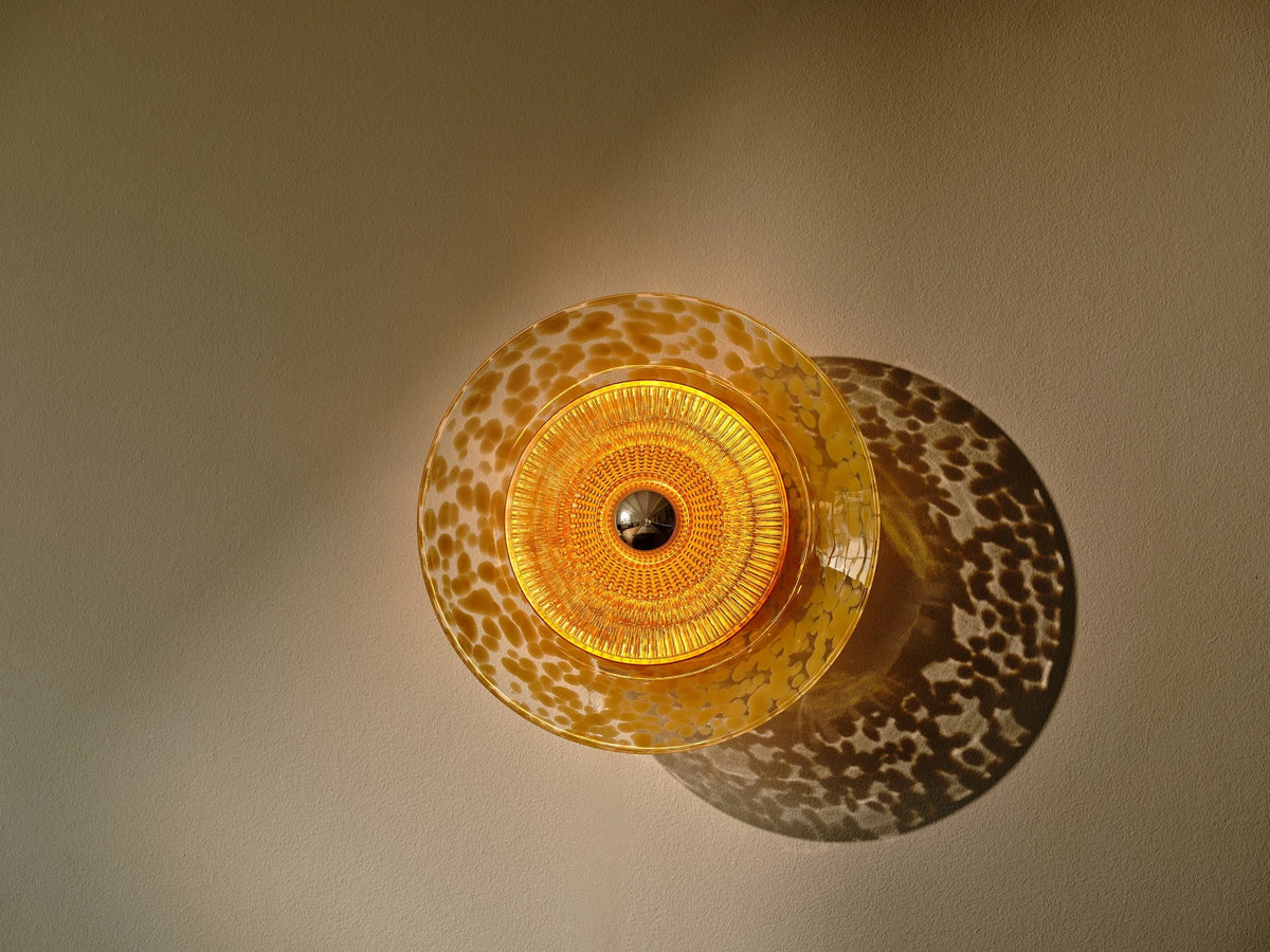 Disco-Rama wall sconce in amber glass casting a warm glow