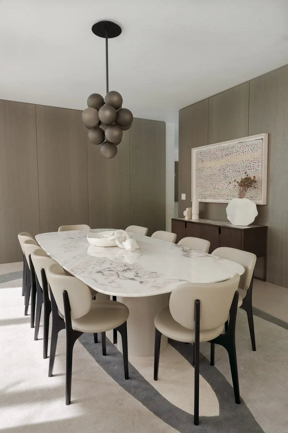 Dining room with a long oval table, cream dining chairs and a cluster pendant