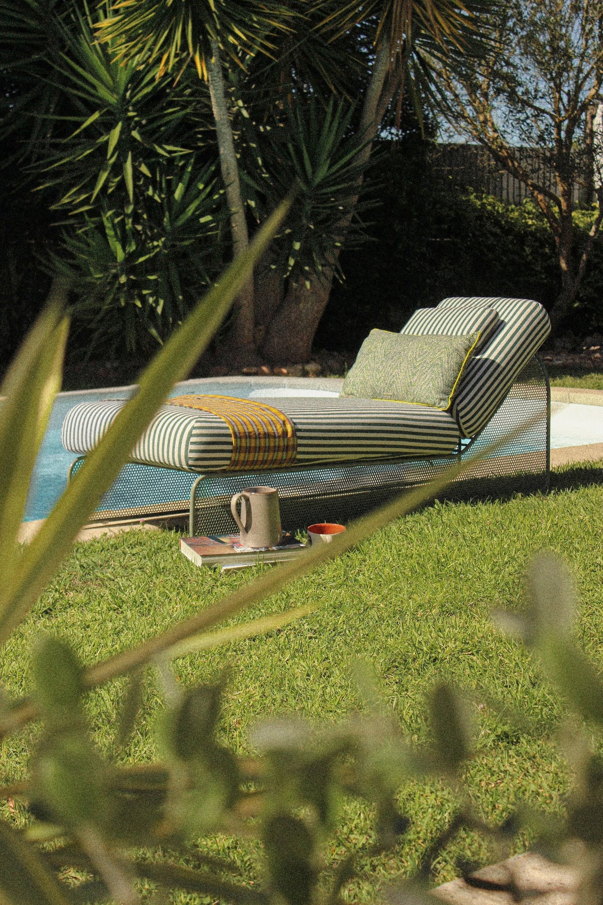 Striped outdoor lounger beside a pool on a lawn