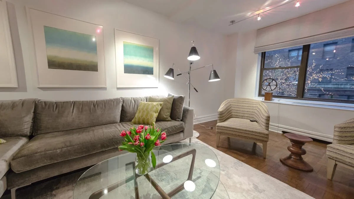 Apartment living room with a grey sectional sofa, glass coffee table and floor lamps