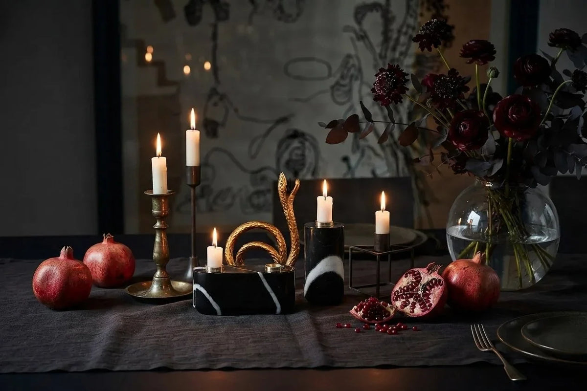 Halloween dinner table set with candles, pomegranates and a marble snake candle holder