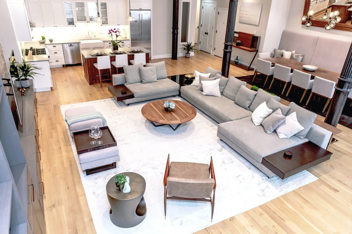 Open-plan loft living room with a grey sectional sofa, round coffee table and dining area