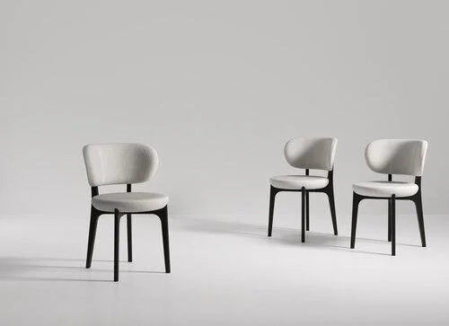 Three grey upholstered dining chairs with black wood legs