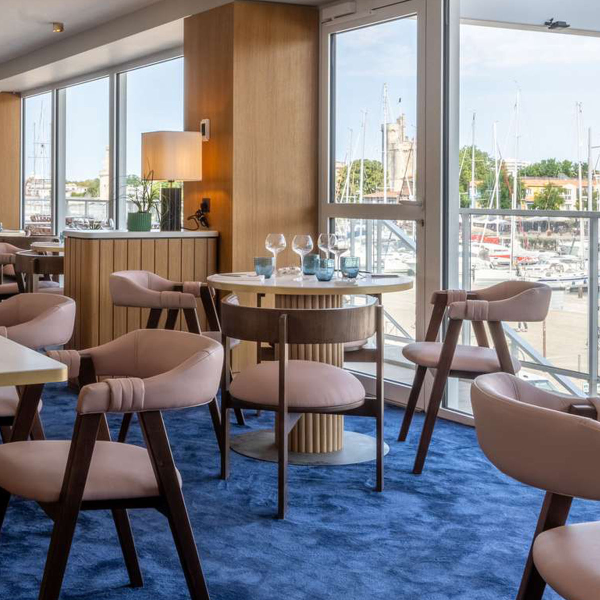 Moulin Dining Chairs in blush upholstery in a waterfront dining room with blue carpet