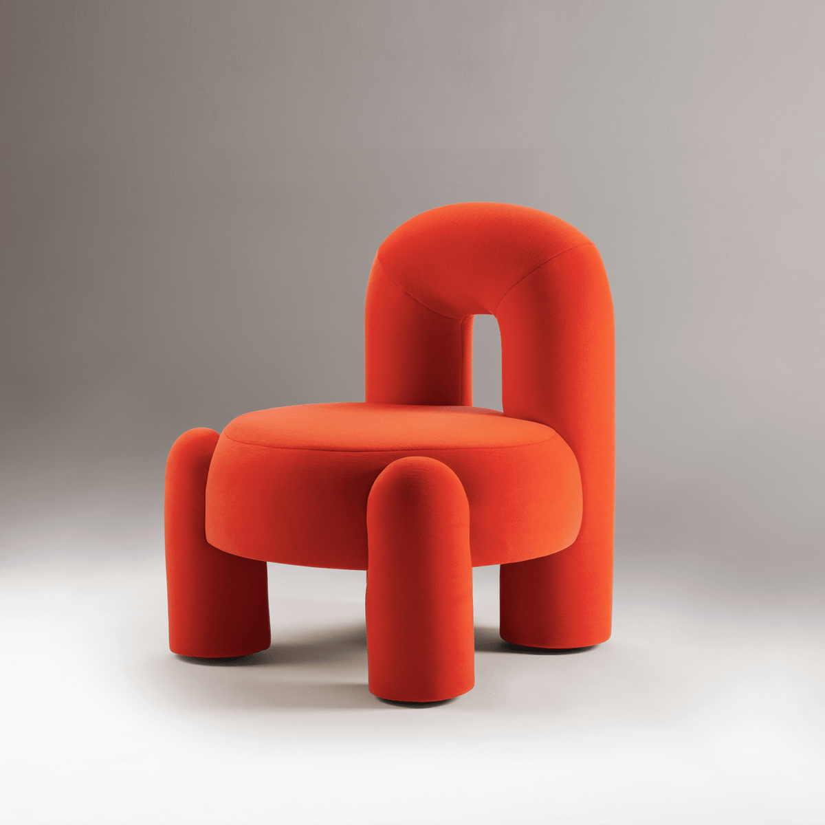 Marlon Armchair in red-orange on a grey backdrop