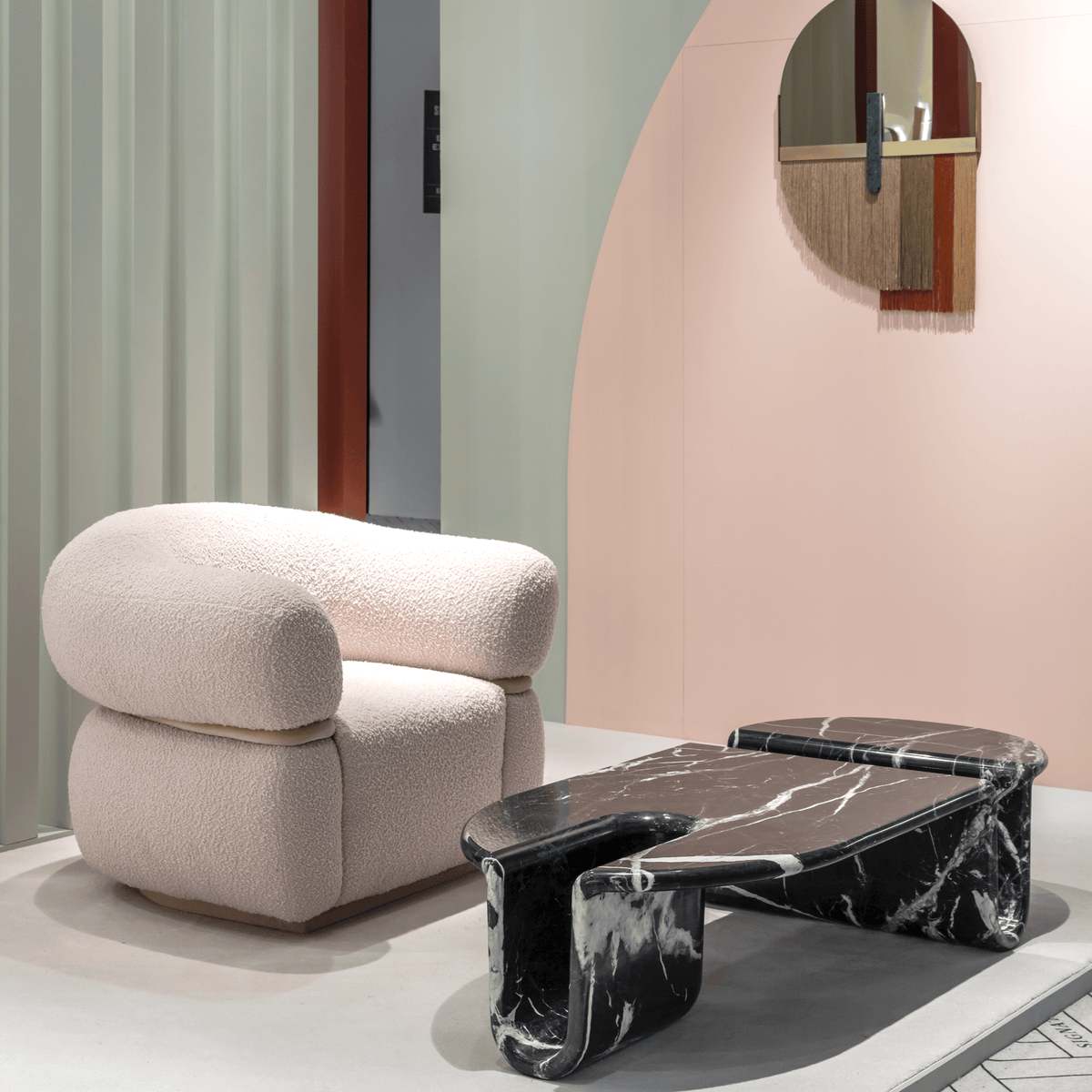 Bonnie & Clyde Coffee Table in Nero Marquina beside a pink bouclé armchair