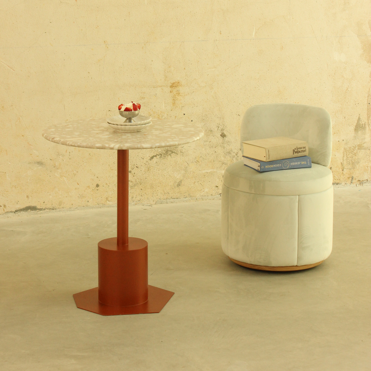 Mimi Swivel Dining Chair in ivory velvet beside a round café table with a red base