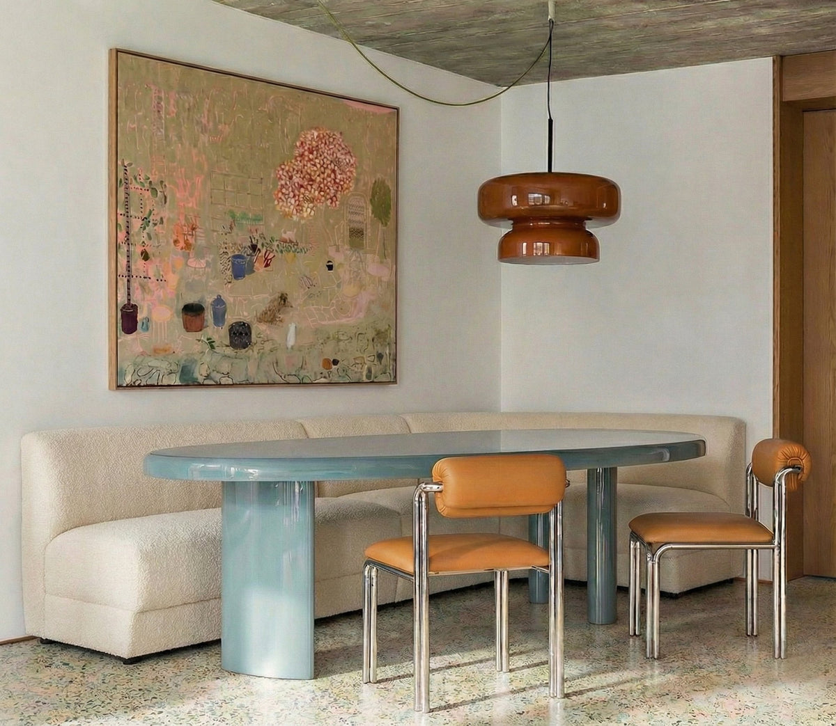 Cubu Chair in tan leather at an oval blue dining table with a cream banquette