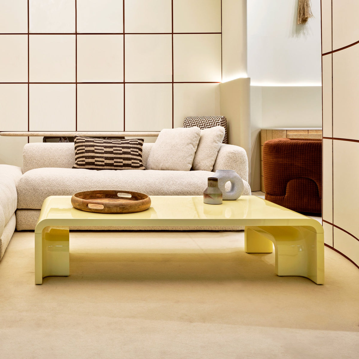 Plié Centre Table in pale yellow lacquer in a cream living room with a sectional sofa