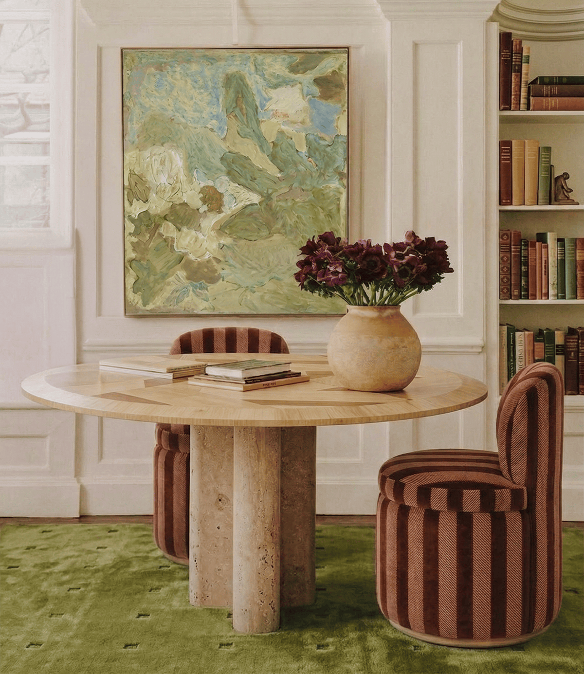 L 'Anamour Dining Table with striped chairs in a library room on a green rug