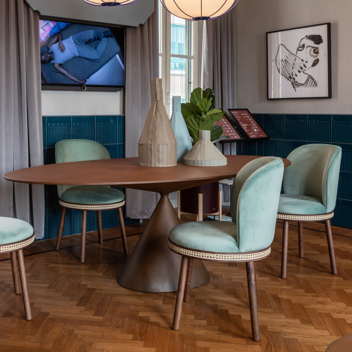 Alma Dining Chair in pale aqua velvet around an oval wooden dining table