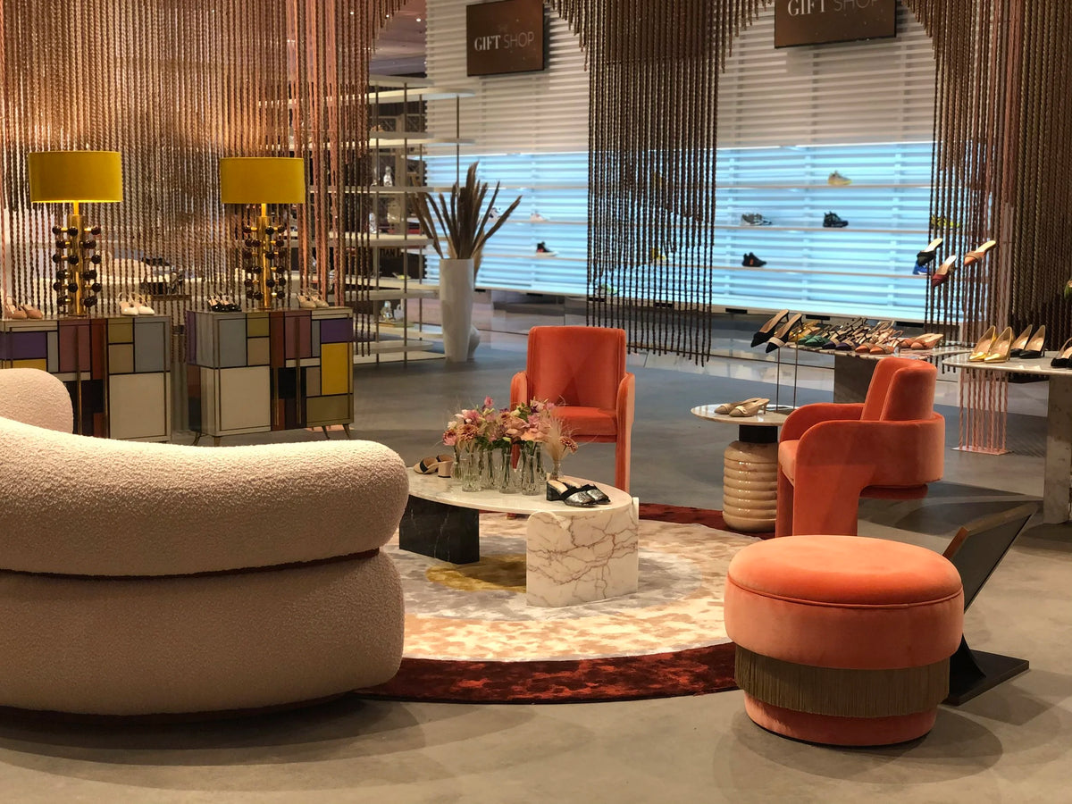 Odisseia Dining Chairs in orange in a colourful boutique lounge with a curved sofa and pouf