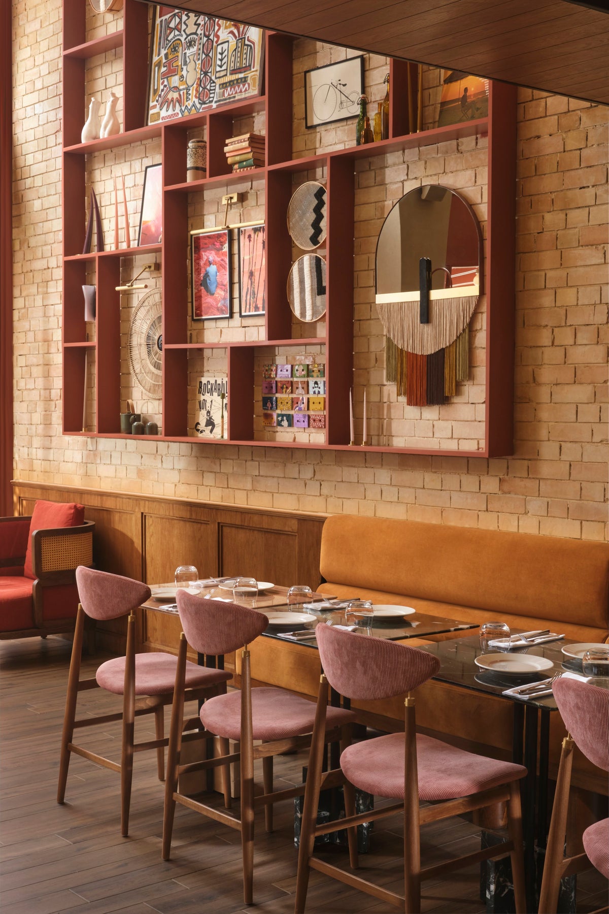 Souk Mirror Caramel on a brick wall in a dining room with pink chairs