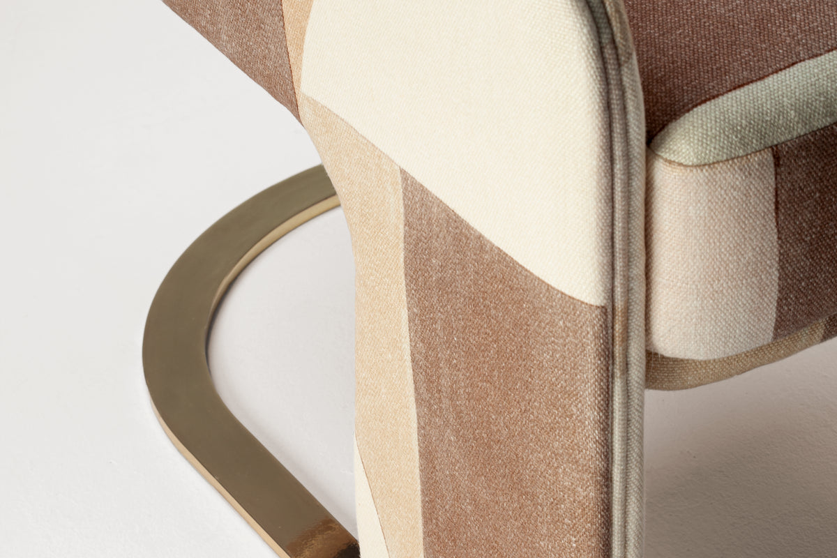 Odisseia Armchair close-up of patterned fabric and curved brass base