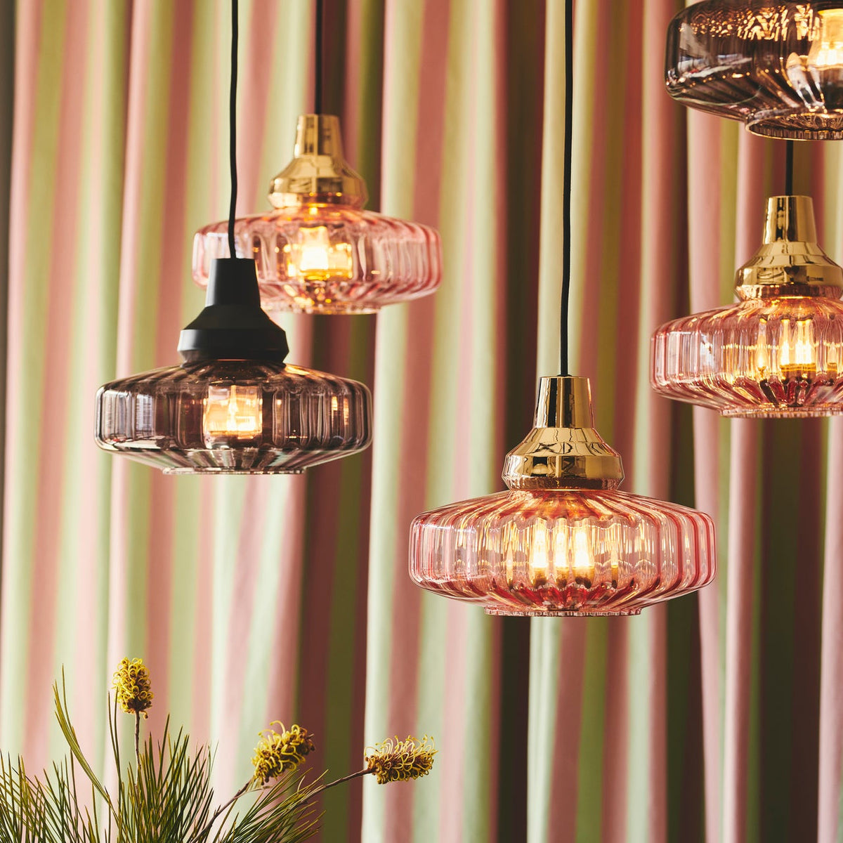 New Wave Optic Pendant Light cluster in Pink and Smoke glass before a striped curtain