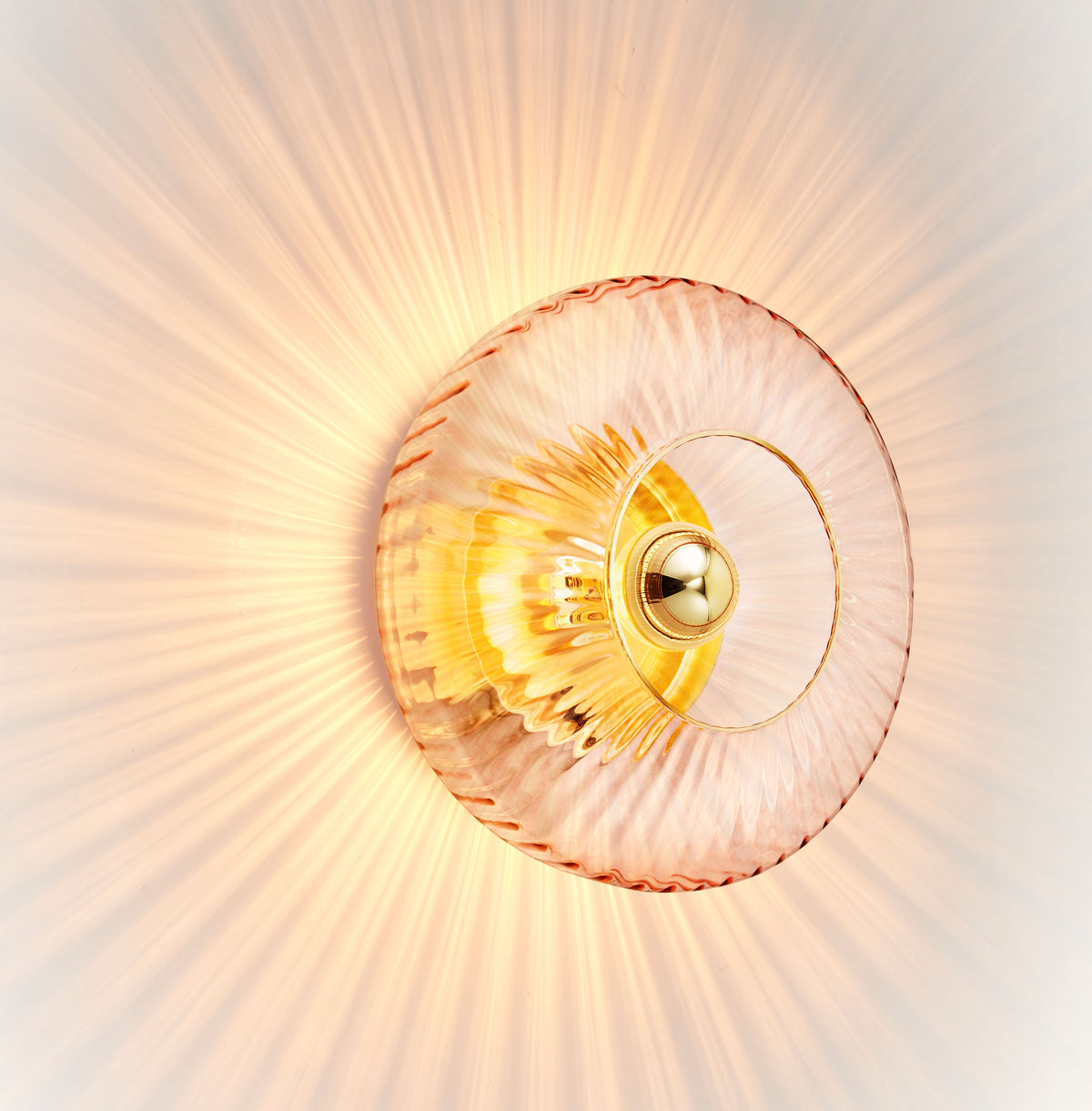 New Wave Optic Wall Sconce XL in Rose glass, angled view glowing on a white wall