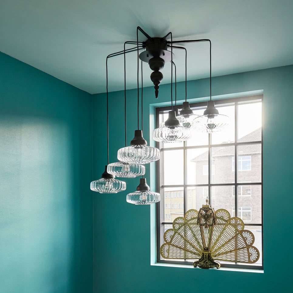 New Wave Optic Pendant Light cluster in Clear glass in a teal room with a peacock fan screen