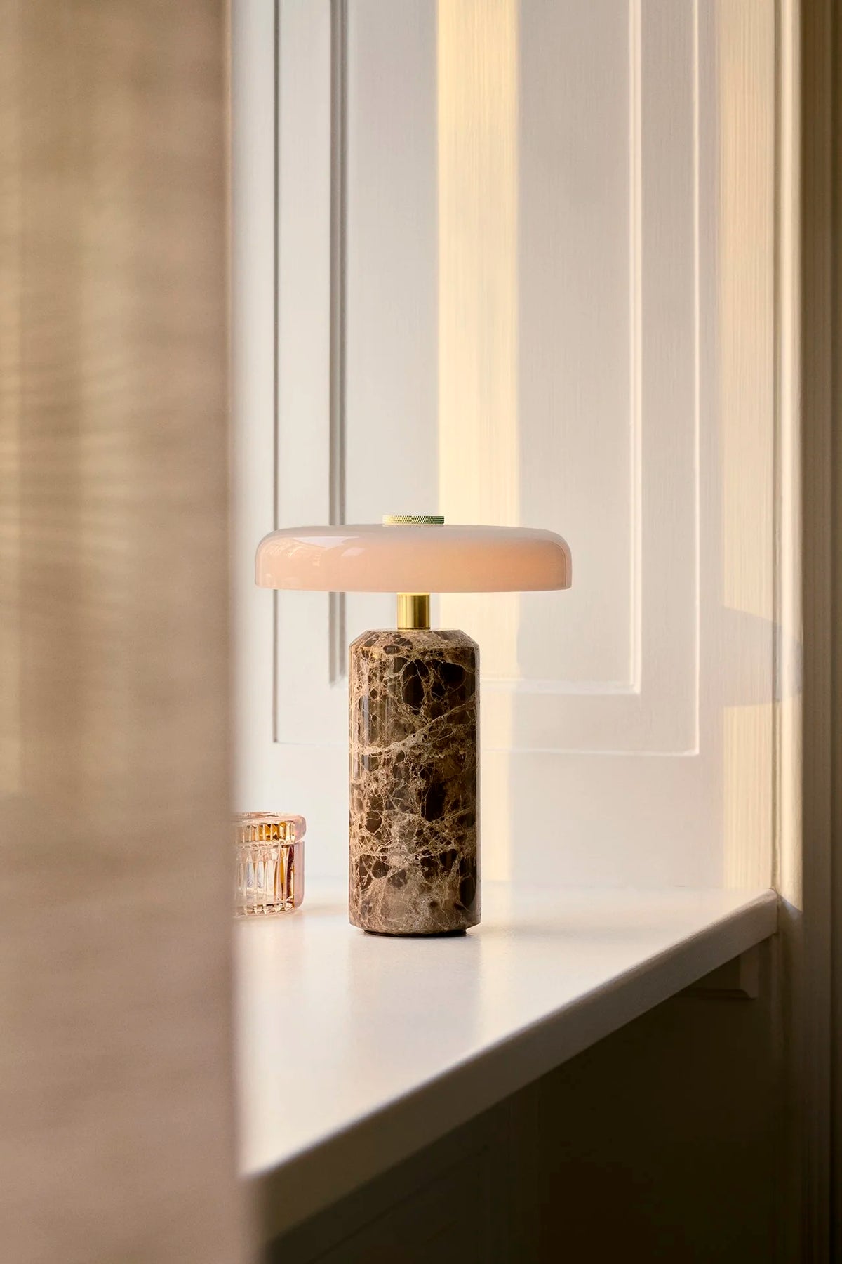 Trip Table Lamp in Dark Emperador marble glowing on a windowsill