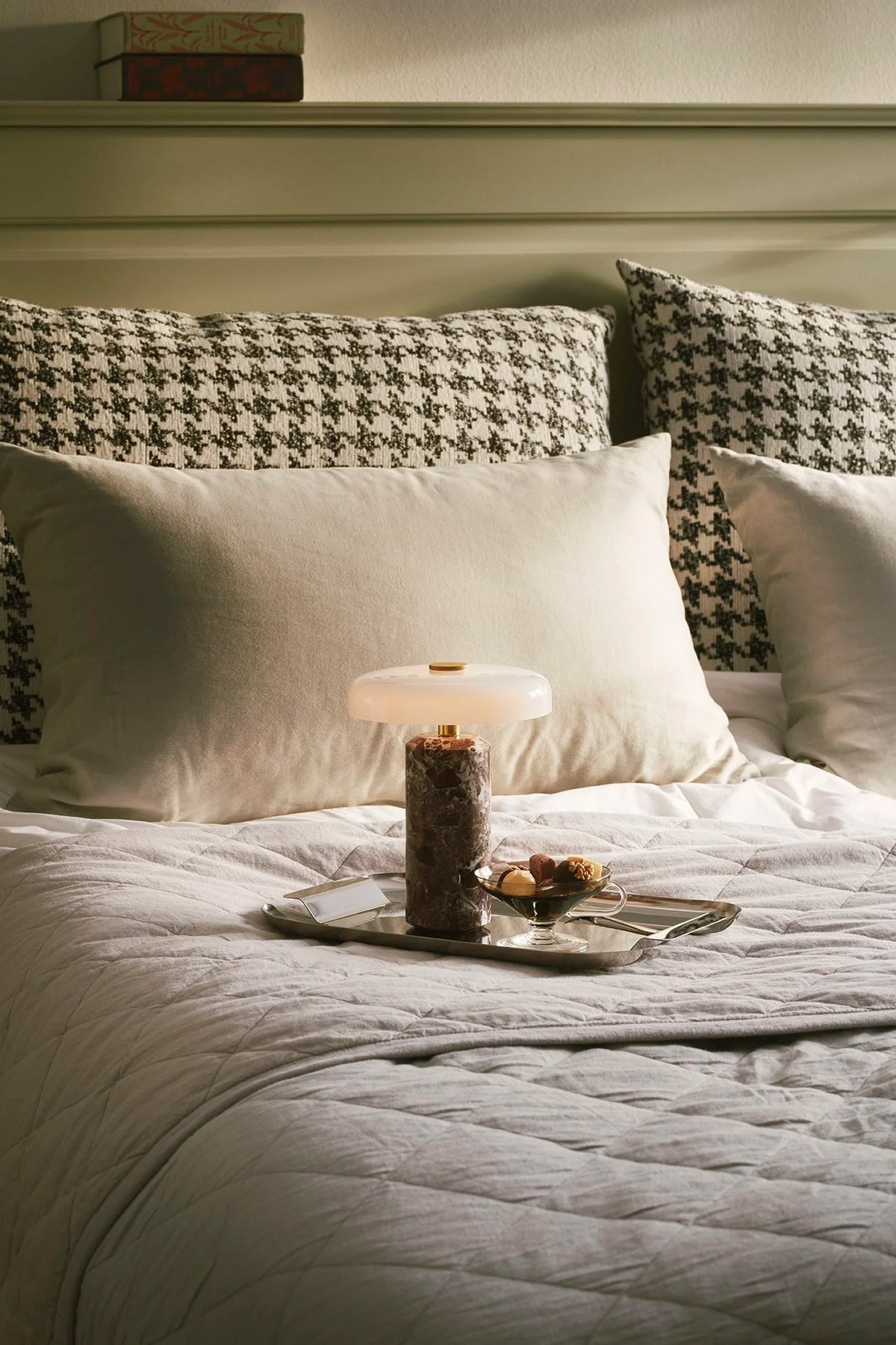 Trip Table Lamp – Burgundy | Opal lit on a tray on a bed with houndstooth pillows