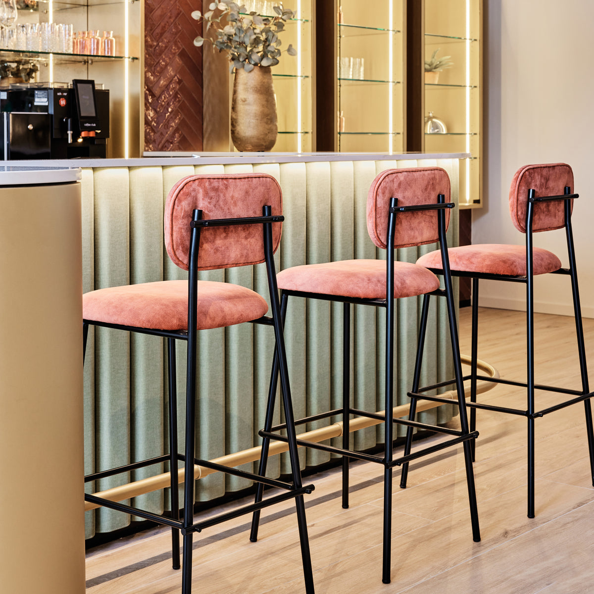Miami Counter Stool in coral velvet with black frame at a bar counter