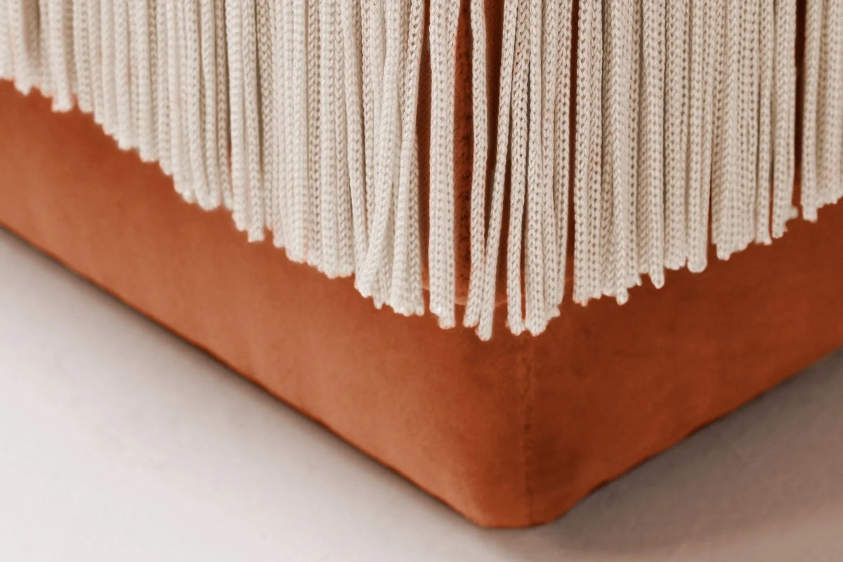 La Folie Sofa close-up of cream fringe over a burnt orange velvet base