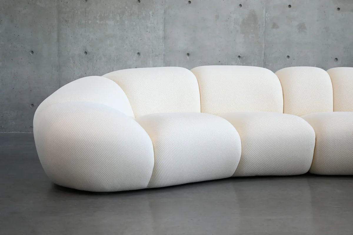 Cirro Sofa - 4-Seater in Buttermilk in a concrete-walled room, side angle