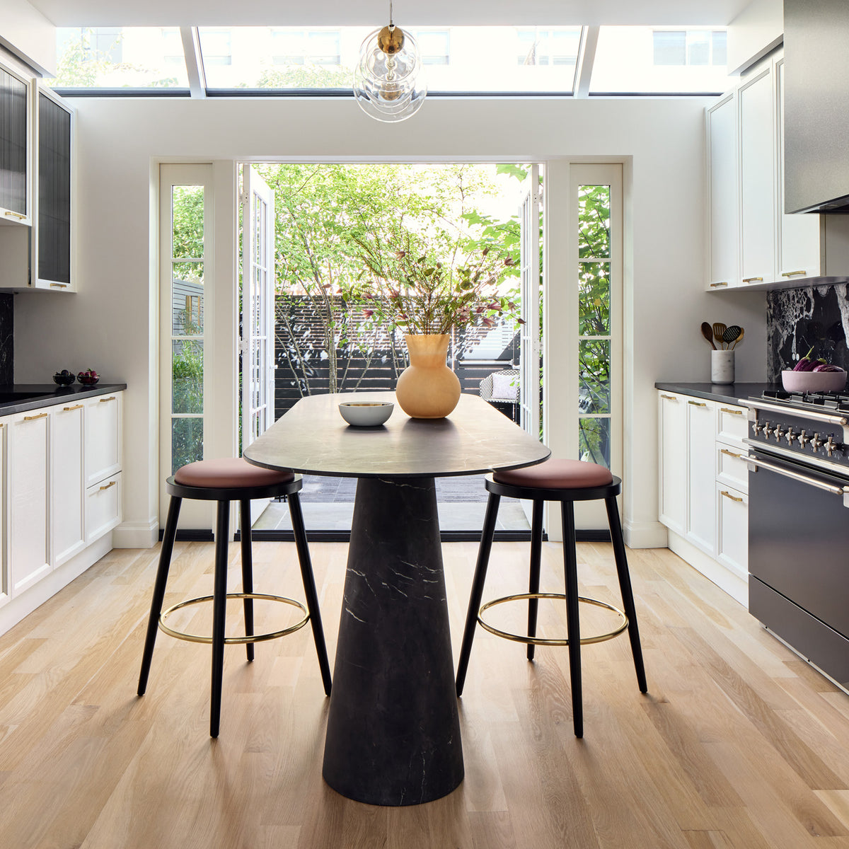 Luc bar stools with black frames at a round dining table in a bright kitchen