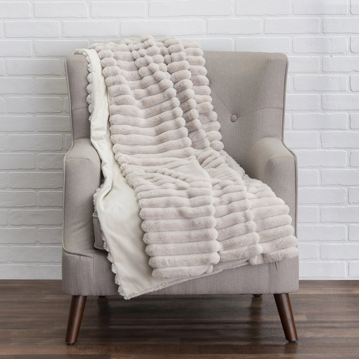 Lux Throw in beige faux fur draped on an armchair by Maison Burgos
