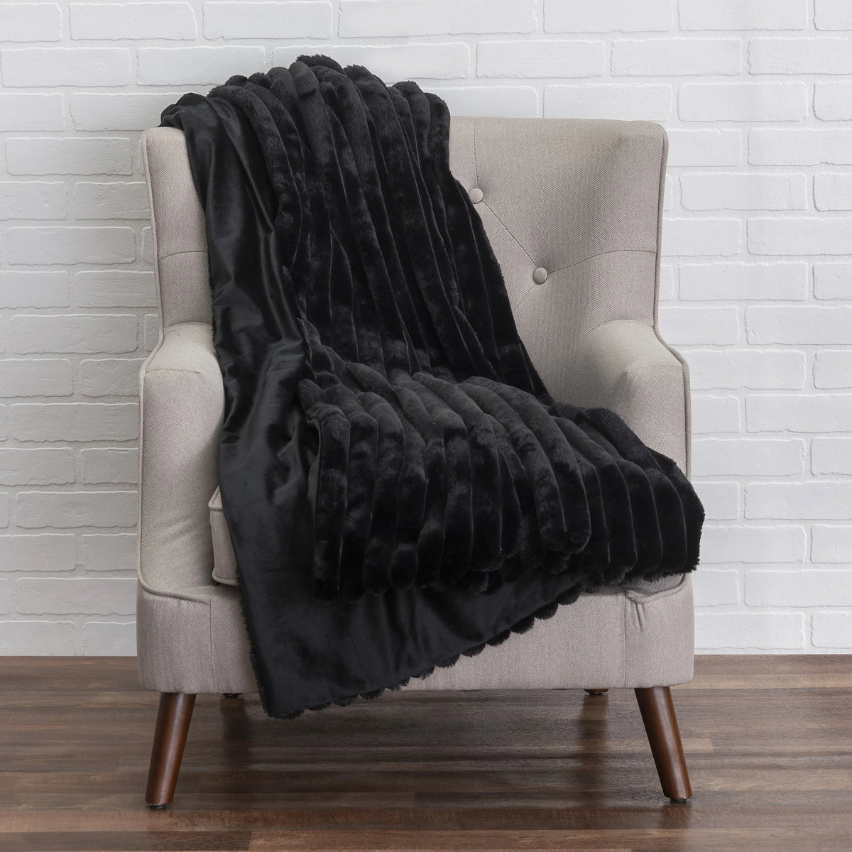 Lux Throw in black faux fur draped on an armchair by Maison Burgos