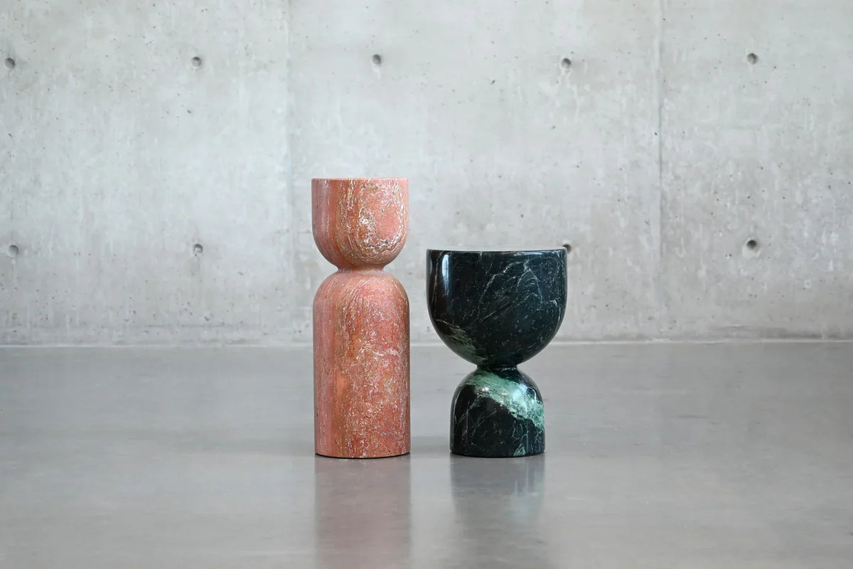 Apothecary End Table in red travertine and green marble pair against a concrete wall