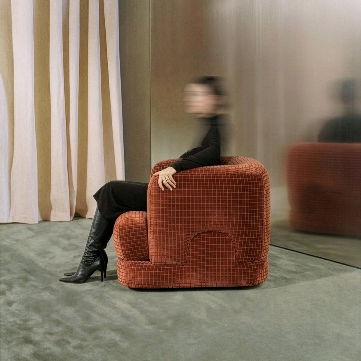 Mosaico Armchair in rust grid velvet with a seated woman beside cream curtains