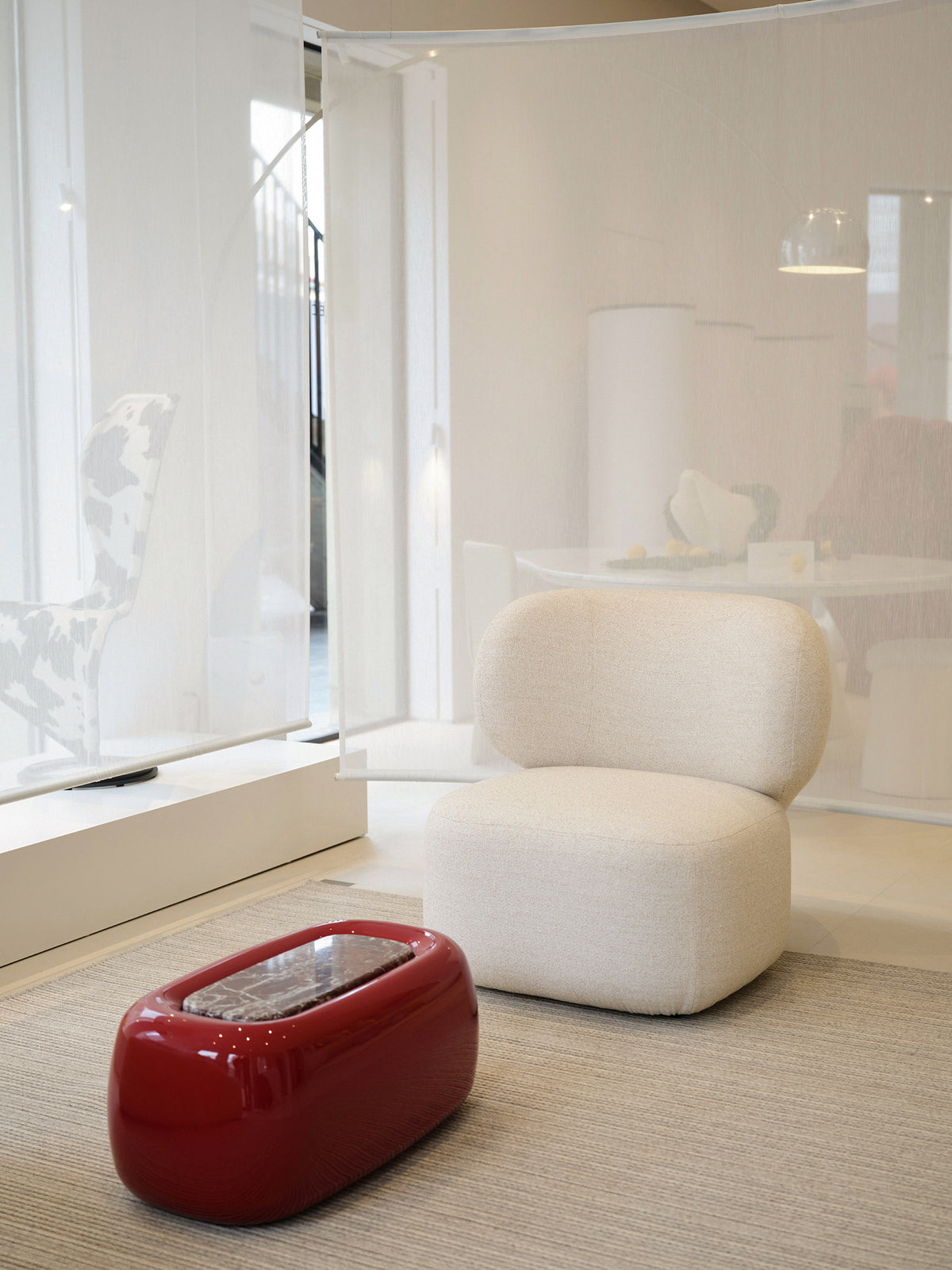 Asawa Lounge Chair in cream bouclé beside a red lacquered table on a natural rug