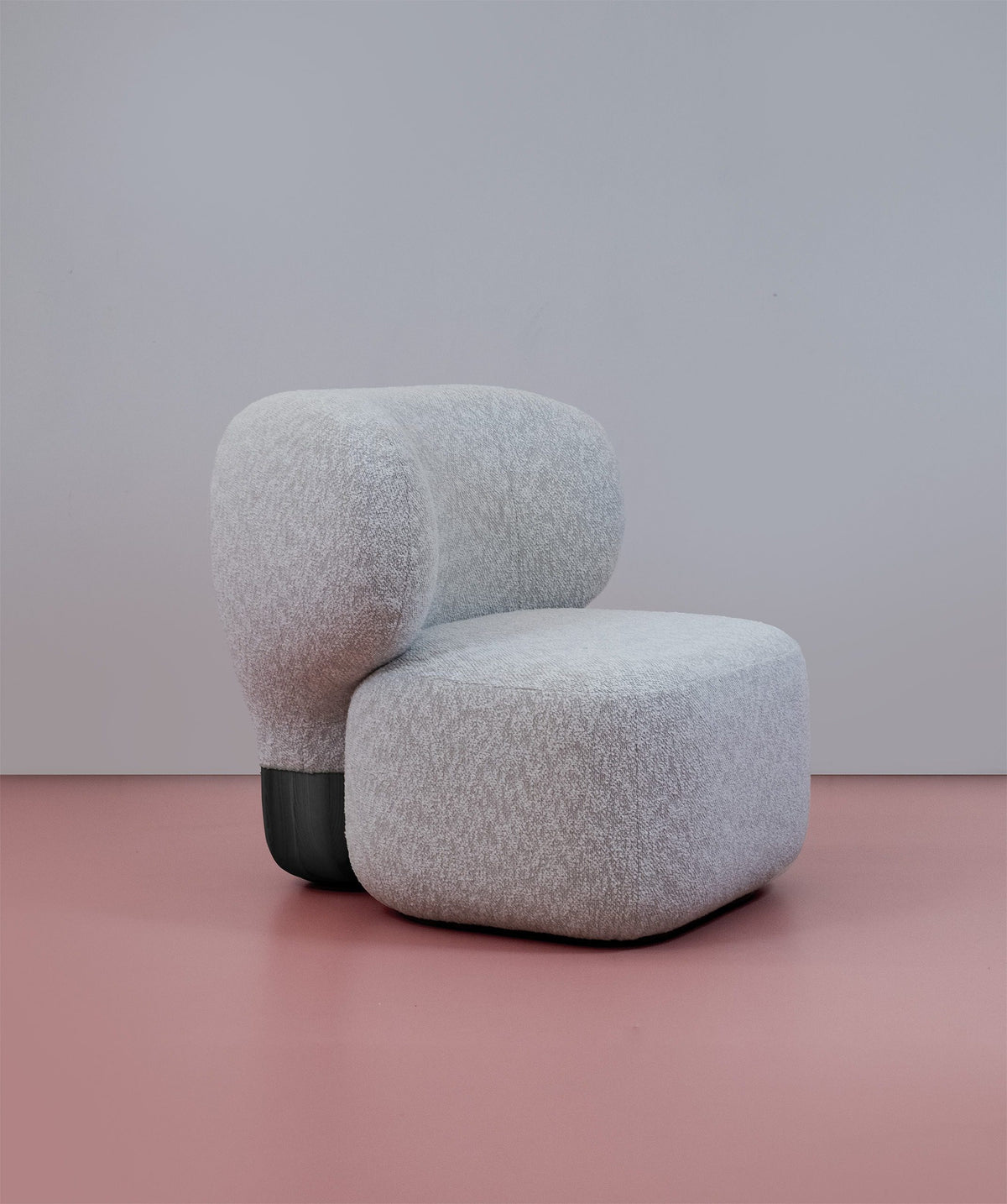 Asawa Lounge Chair in grey bouclé with black base, three-quarter view on a pink floor