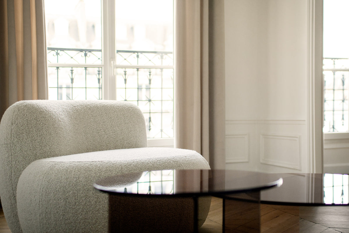 B-15 Z Lounge Chair in cream bouclé beside a smoked glass coffee table by tall windows