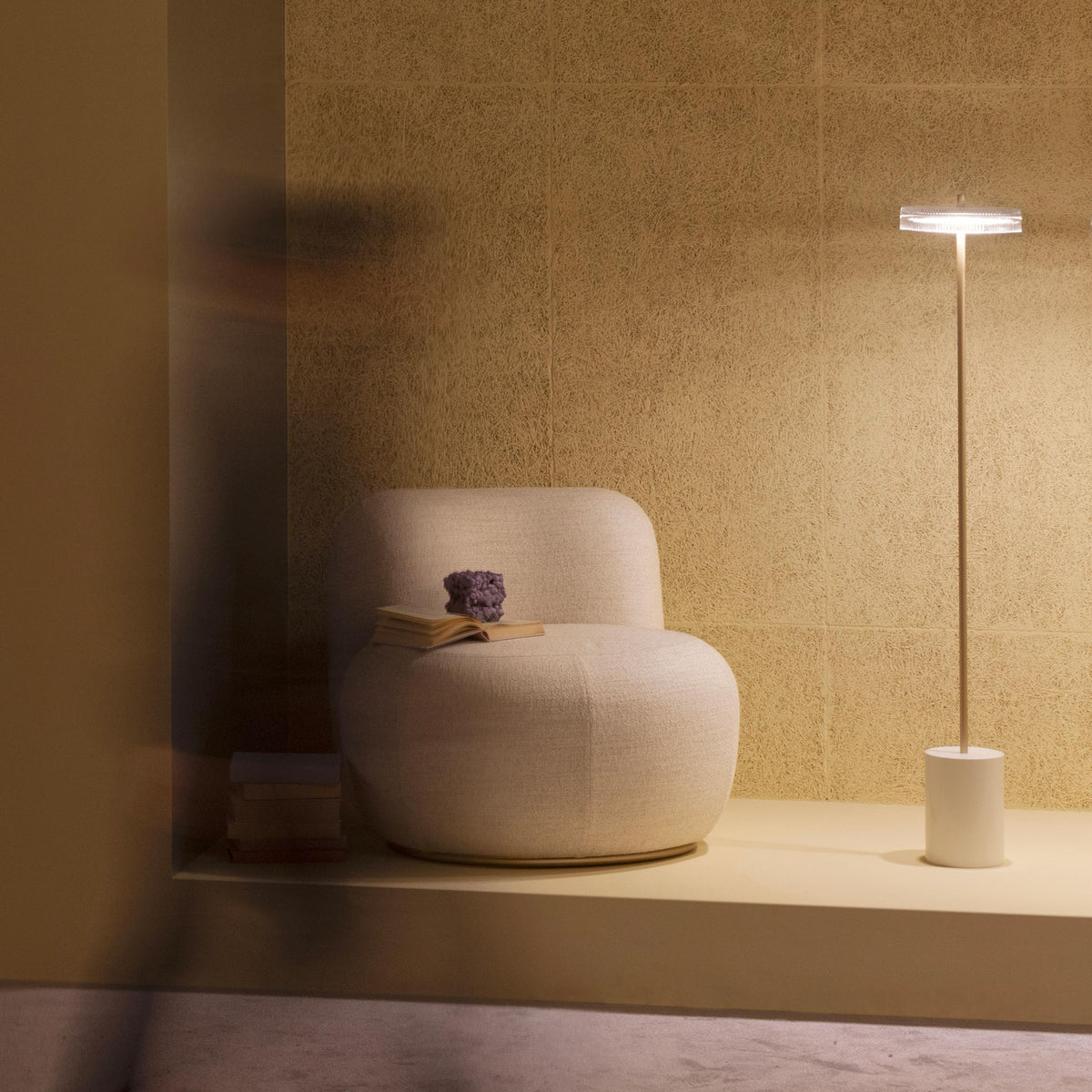 B-15 Z Lounge Chair in blush bouclé with a book on the seat beside a floor lamp