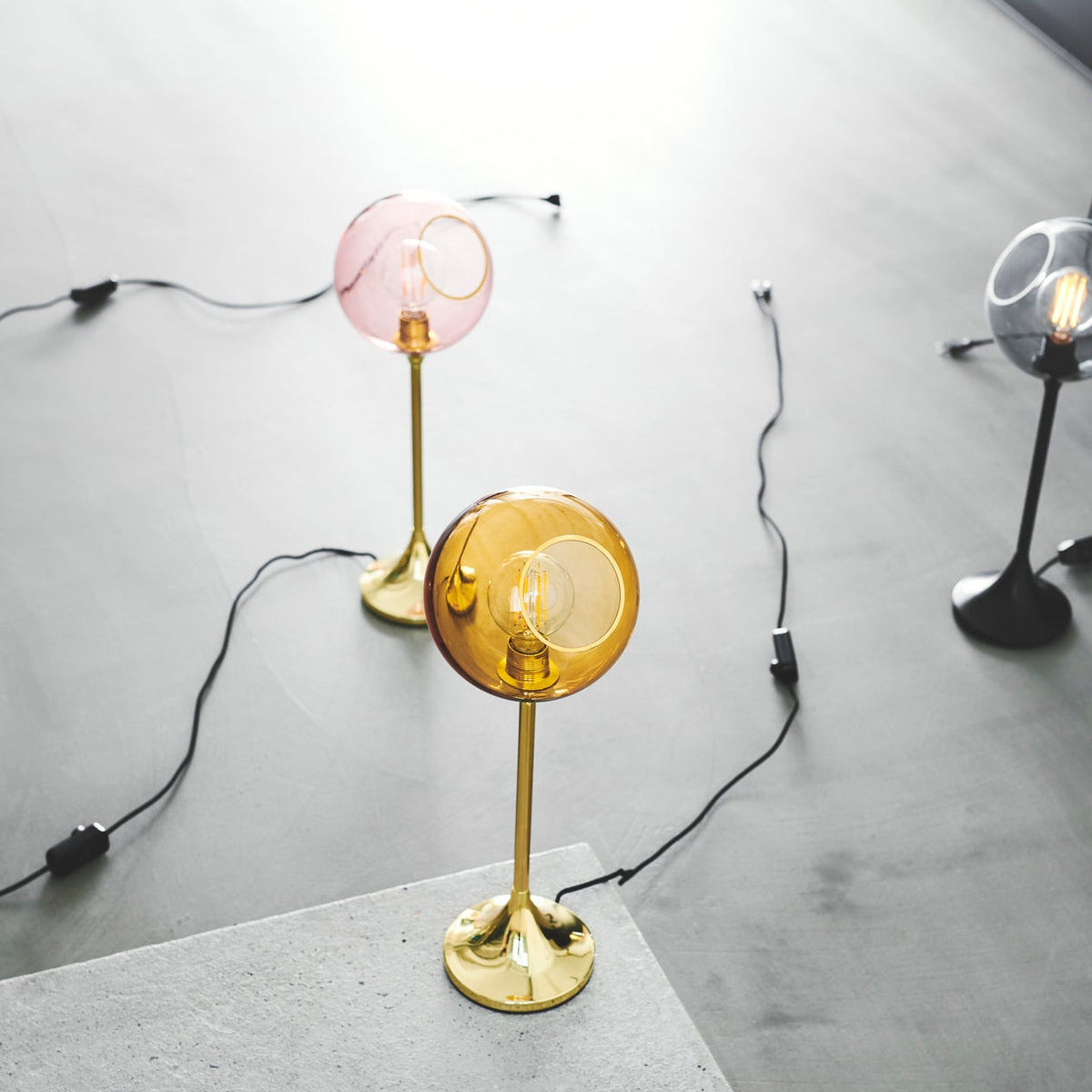 Ballroom Table Lamp in Pink and Amber glass with gold bases on a concrete floor