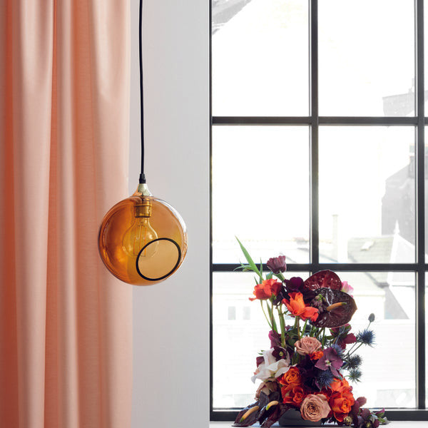 Ballroom Amber Pendant Light, amber glass globe by a window with flowers