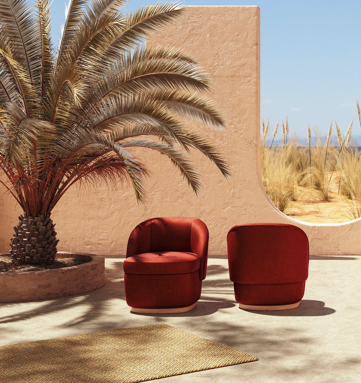 Bisou Armchair pair in rust red on a sunny terrace beside a palm