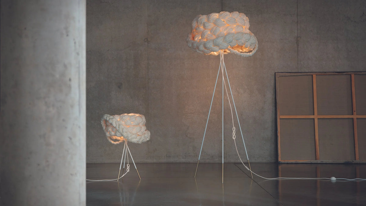 Mammalampa Bride Floor Lamp in white braided paper glowing in a dark concrete room