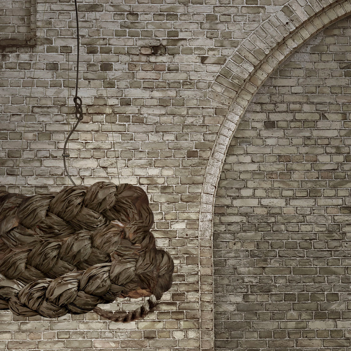 Mammalampa Bride Pendant Light Brown hanging against an old brick wall