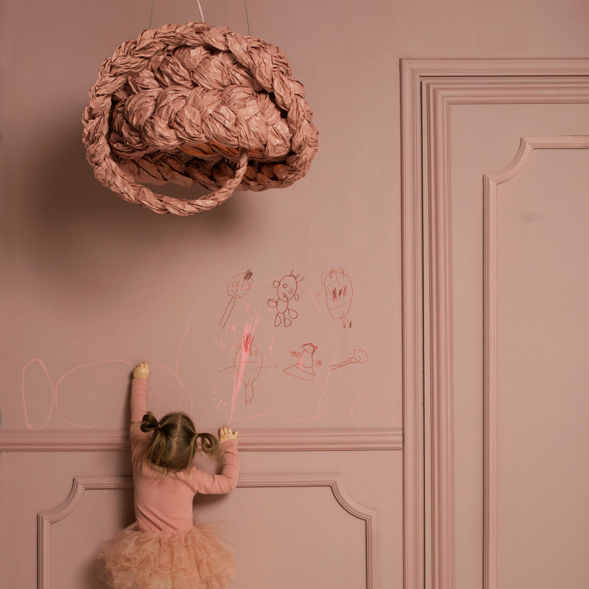 Mammalampa Bride Pendant Light in pink hanging above a child drawing on a pink panelled wall