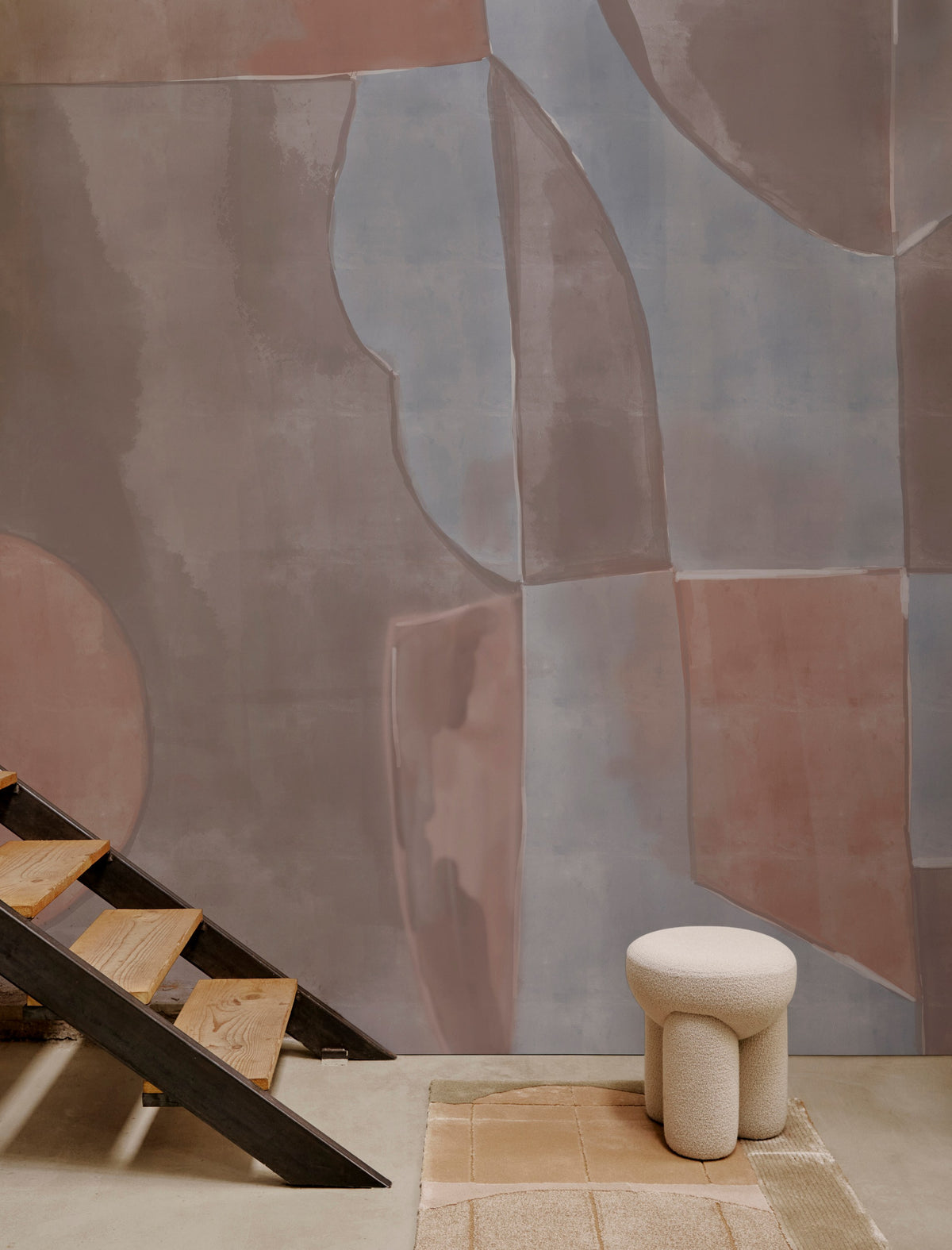 Douglas Ottoman in cream bouclé before a painted mural wall with stairs