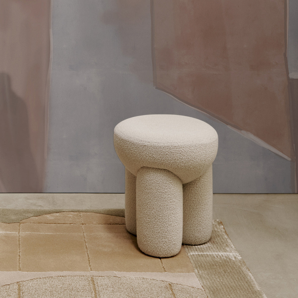 Douglas Ottoman in cream bouclé on a rug, closer three-quarter view