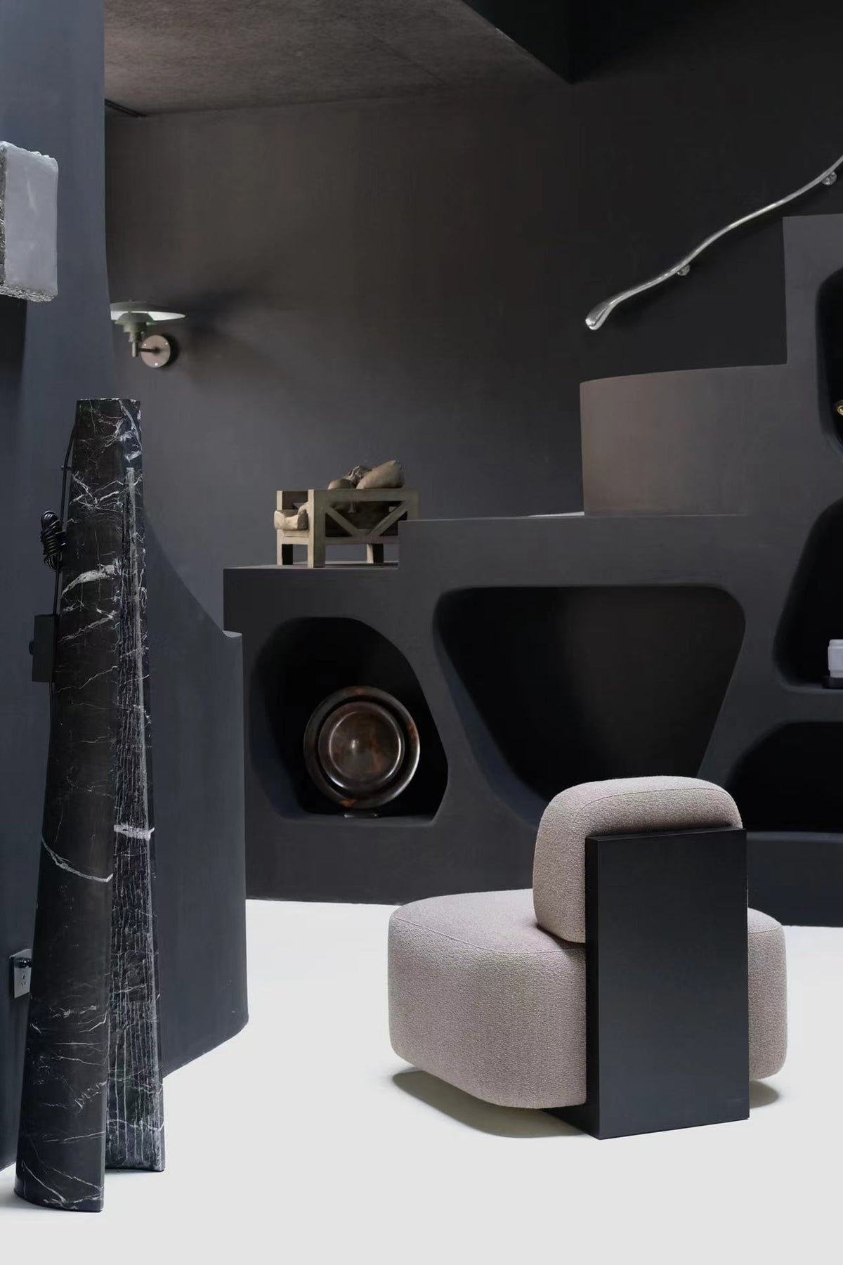 Yoshida Lounge Chair in pale grey with a black side panel in a dark sculptural interior