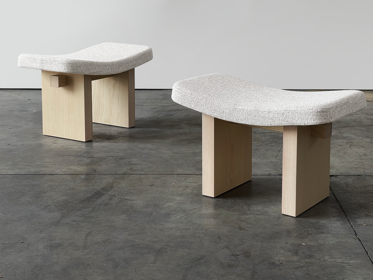 Nara Ottoman pair in ivory bouclé on light wood legs in a concrete room