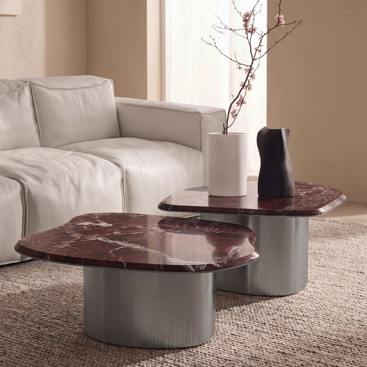 Fragment Coffee Tables in red marble with metal bases beside a sofa, wider view