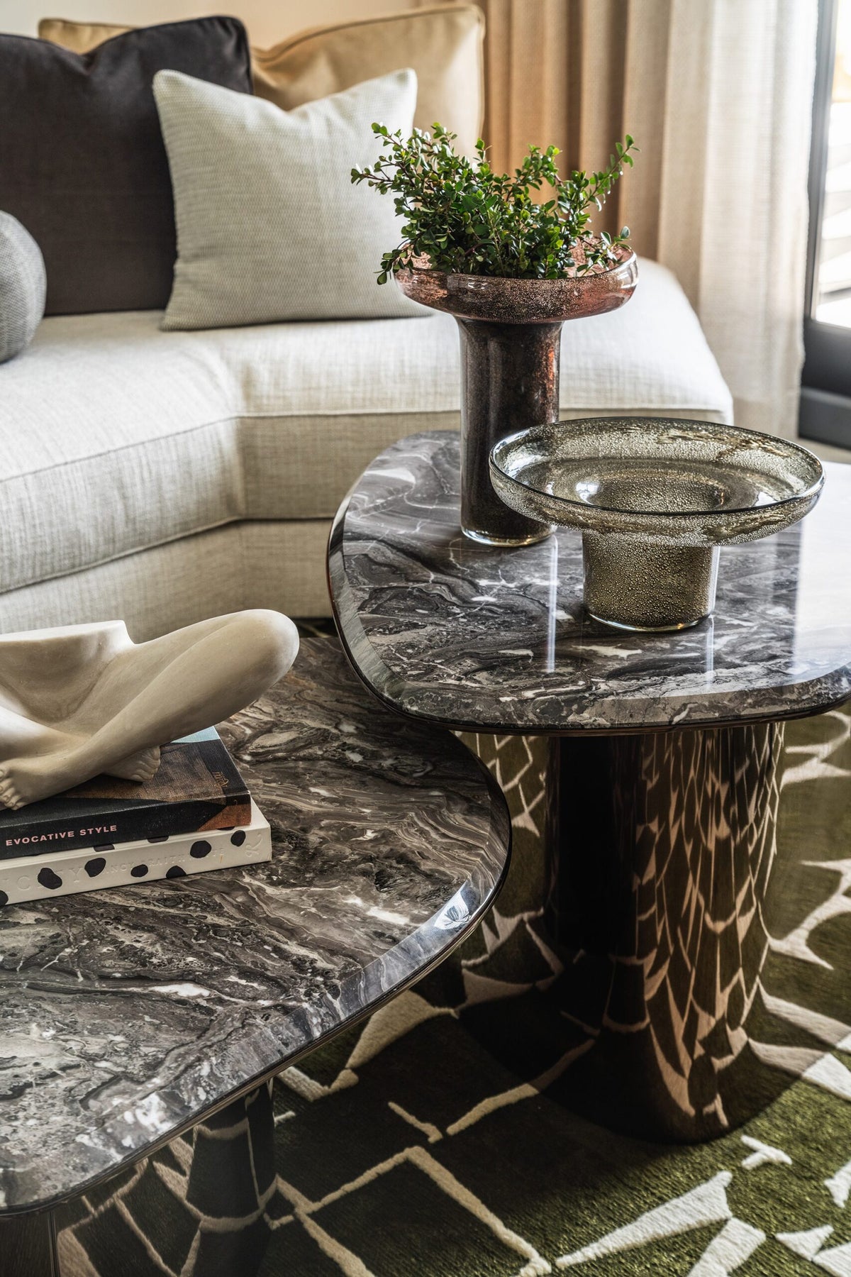 Fragment Coffee Tables in grey veined marble beside a curved sofa