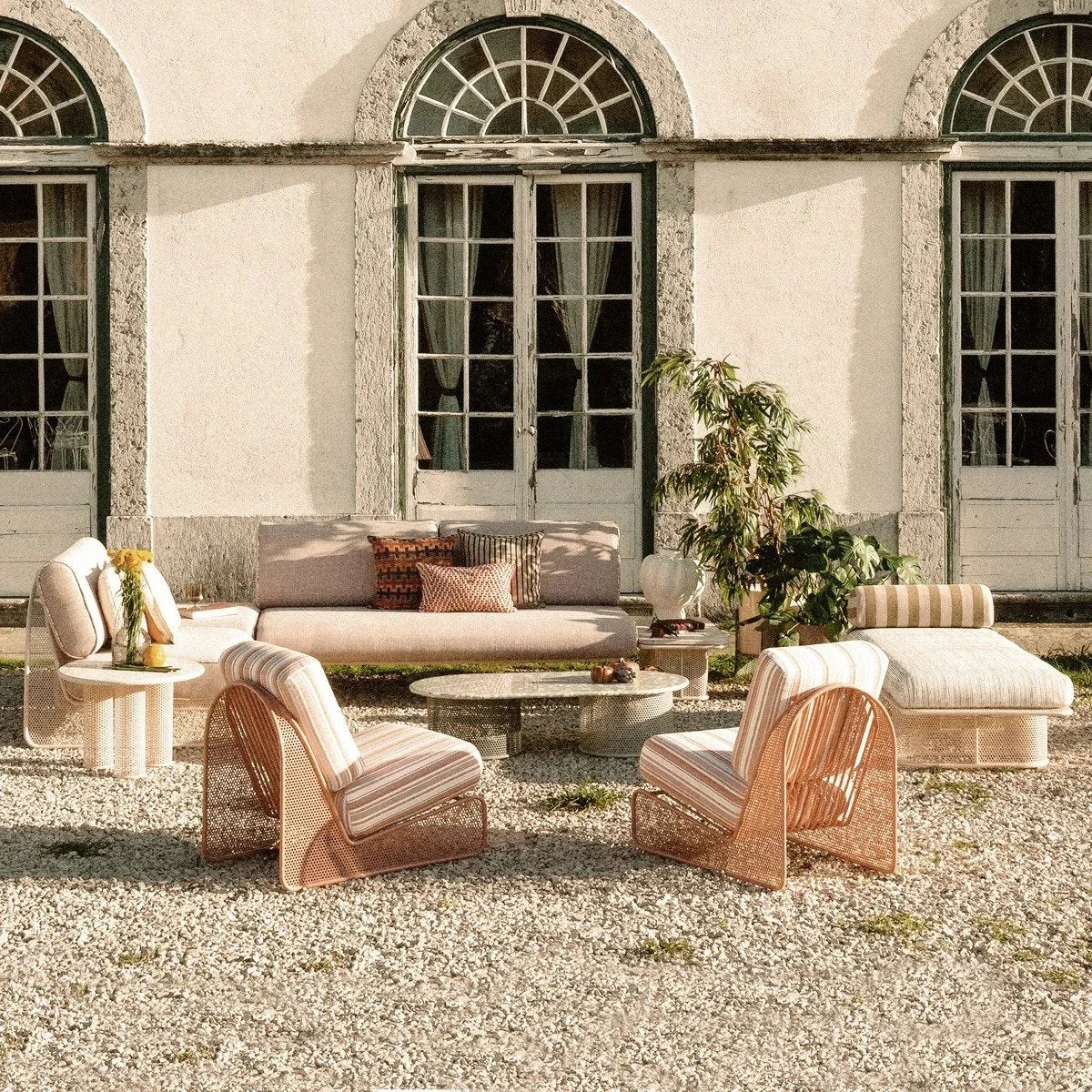 Riviera Armchairs with Awning Stripe cushions on a gravel terrace before a villa