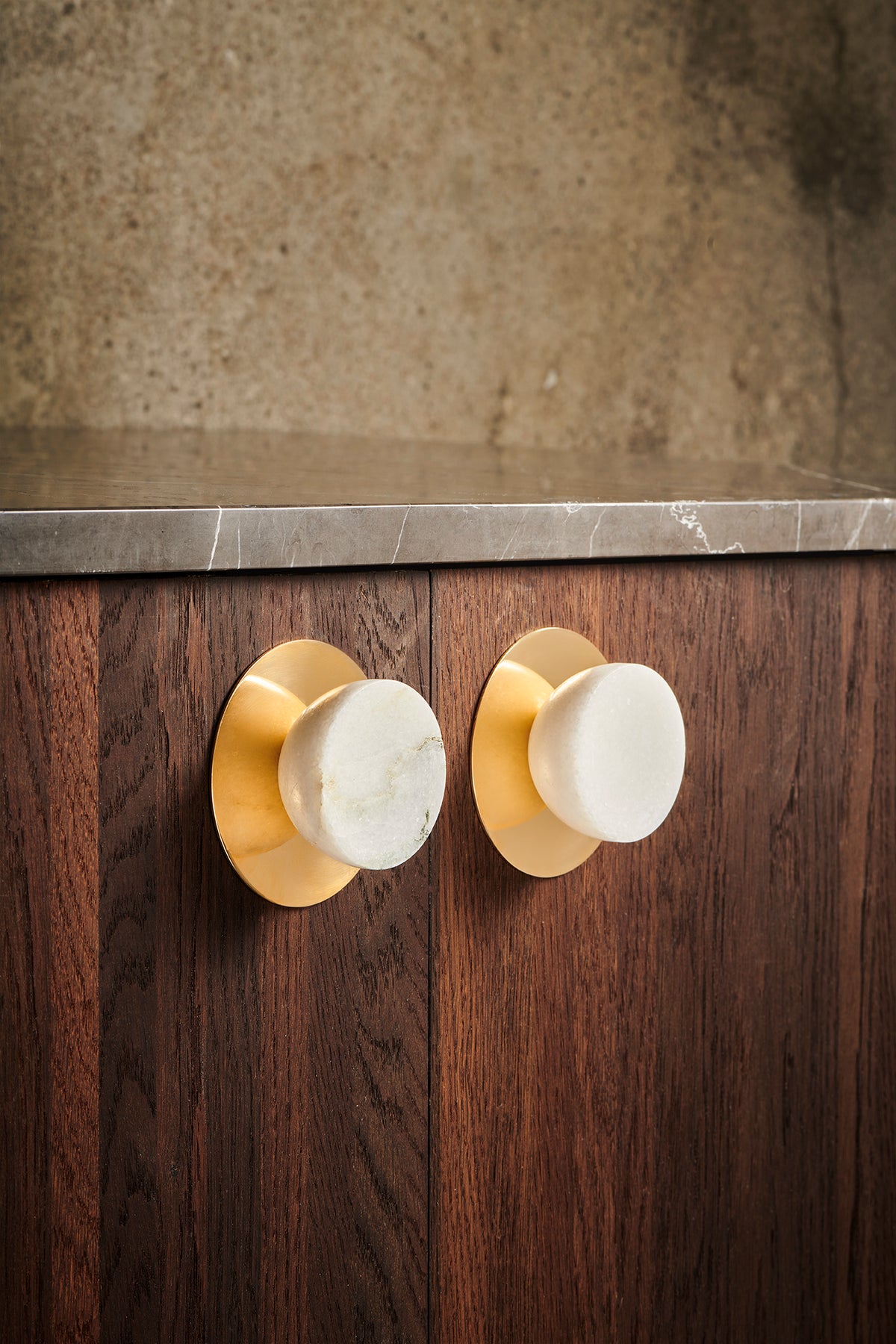 Get a Grip brass backplate with white marble knob on a walnut cabinet by Maison Burgos